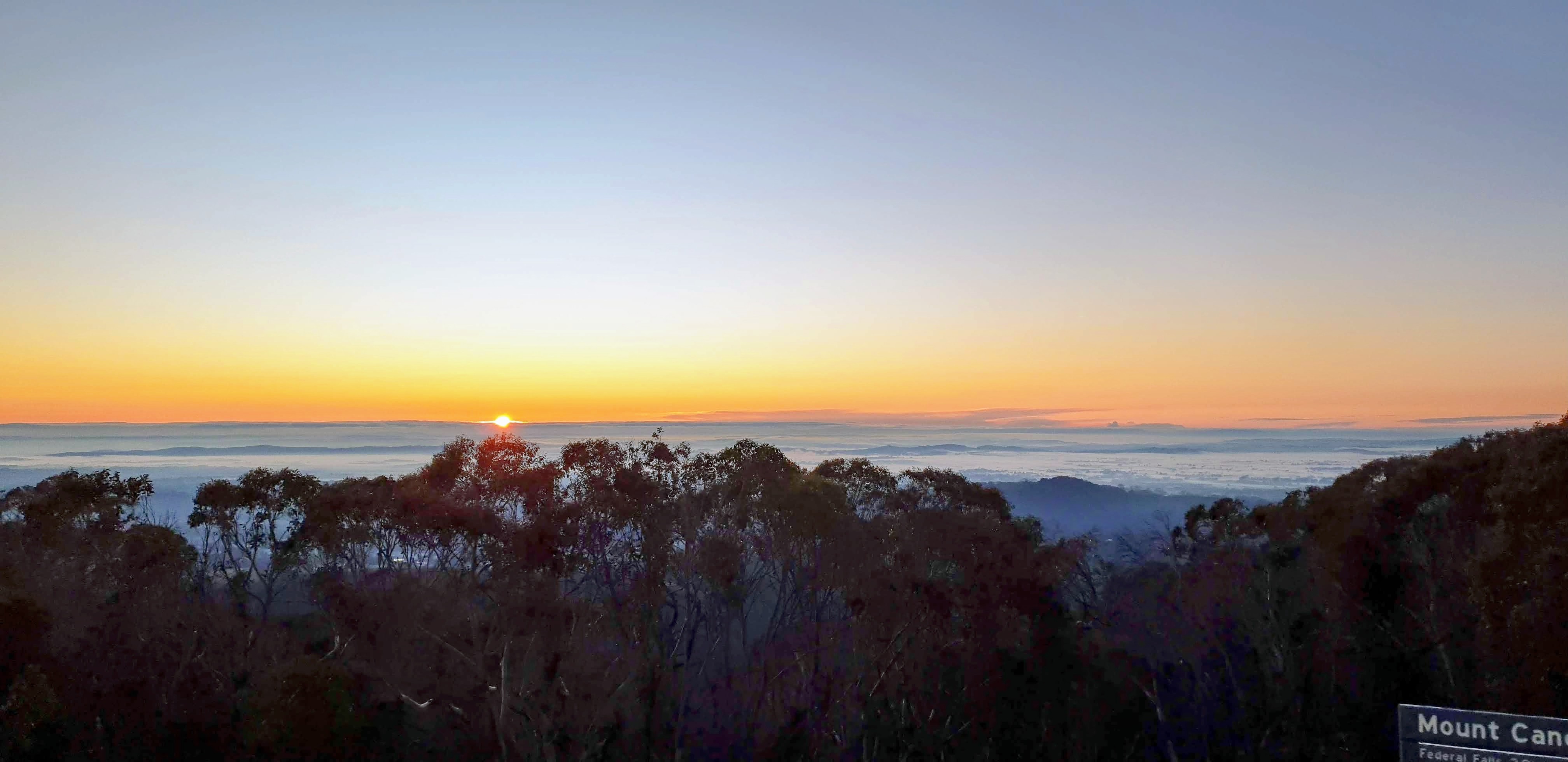 Golden sunrise over mist-filled Australian ridgelines and forest
